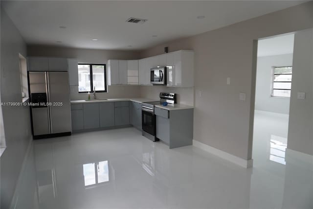 kitchen with stainless steel appliances, a sink, modern cabinets, gray cabinets, and light countertops