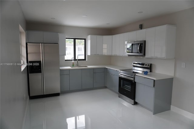 kitchen featuring appliances with stainless steel finishes, a sink, gray cabinets, modern cabinets, and light countertops