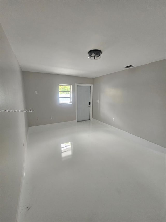 unfurnished room with finished concrete floors and baseboards