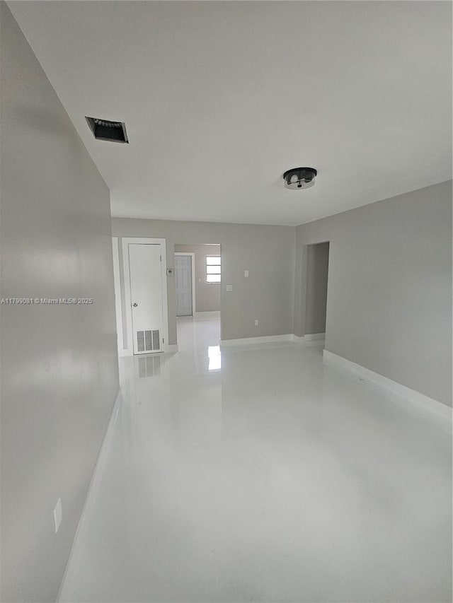 unfurnished room with baseboards and finished concrete flooring