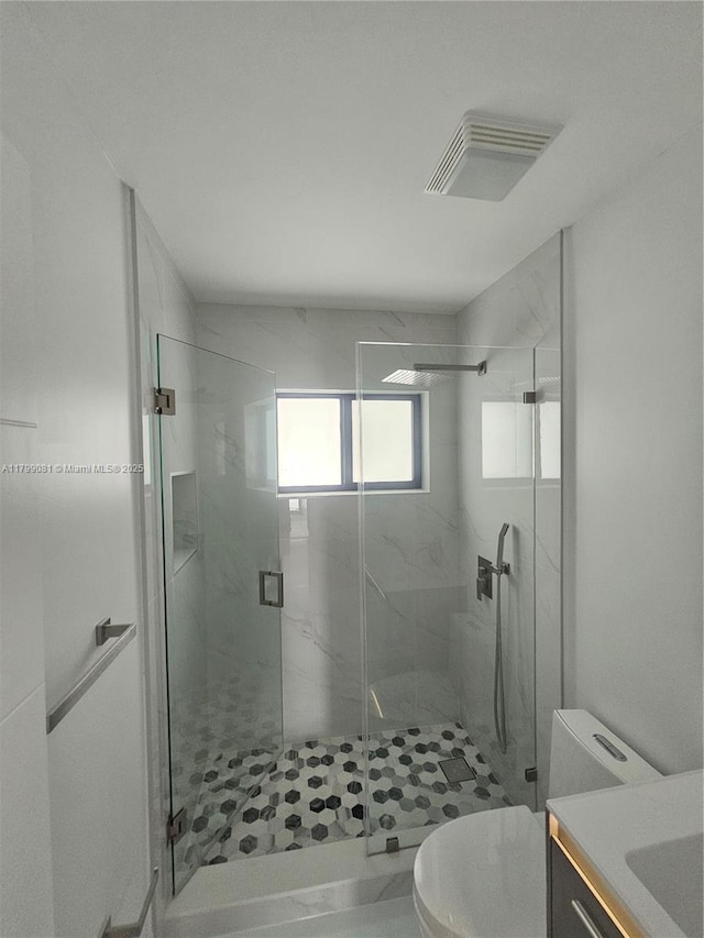 full bath with toilet, a marble finish shower, and vanity