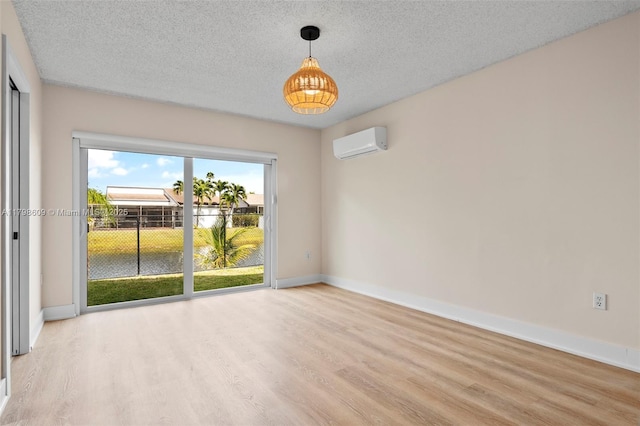 16791 Royal Poinciana Dr, Weston, FL 33326 - empty room with an AC wall unit, light wood-style floors, baseboards, and a textured ceiling