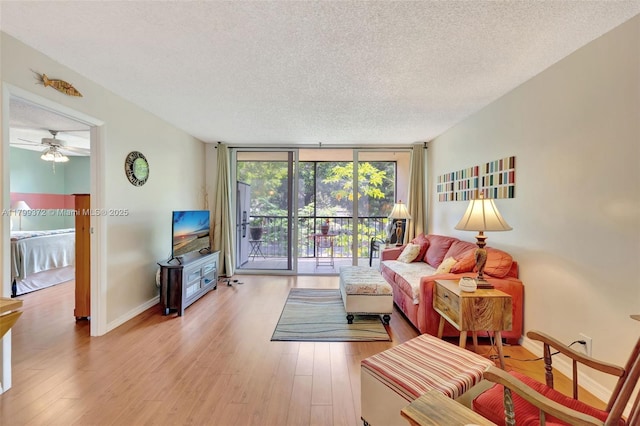 7080 Environ Blvd Unit 223, Lauderhill, FL 33319 - living area with a textured ceiling, wood finished floors, a wall of windows, baseboards, and a ceiling fan
