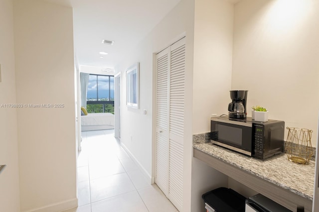 corridor featuring light tile patterned floors and baseboards