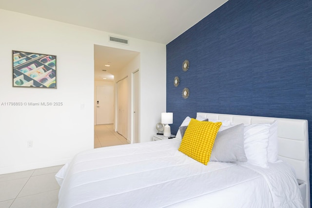 bedroom featuring tile patterned floors, an accent wall, wallpapered walls, and baseboards