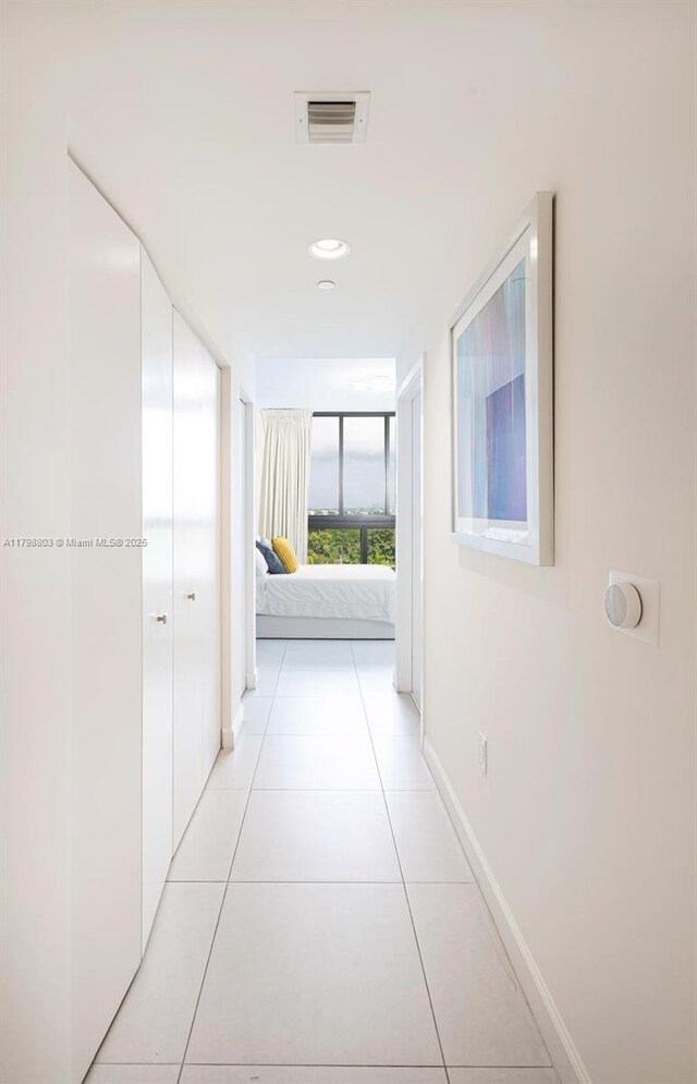 hall featuring light tile patterned floors and baseboards