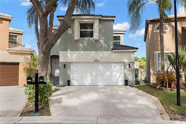 mediterranean / spanish-style home featuring an attached garage, driveway, a tiled roof, and stucco siding