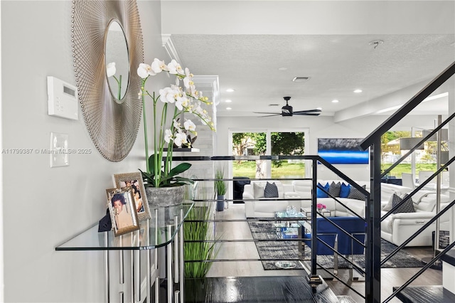 stairway featuring a ceiling fan, recessed lighting, a textured ceiling, and wood finished floors
