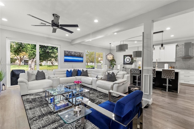 living room with wood finished floors, a ceiling fan, recessed lighting, and ornamental molding