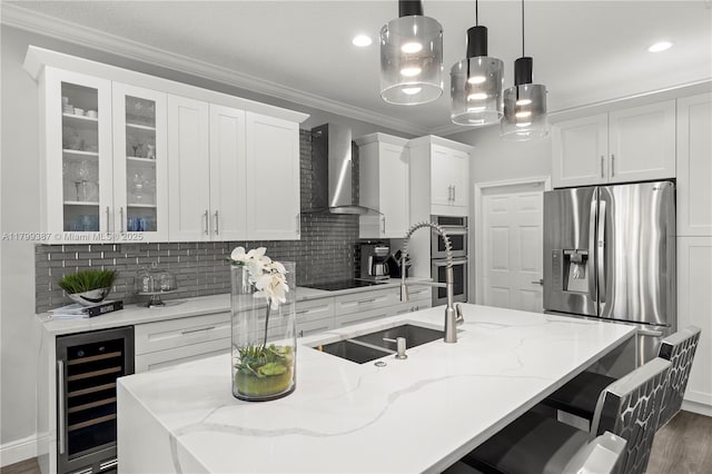 kitchen featuring beverage cooler, wall chimney exhaust hood, stainless steel appliances, white cabinetry, and ornamental molding