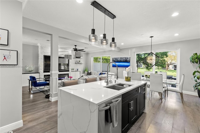 kitchen with a sink, stainless steel dishwasher, dark cabinets, recessed lighting, and wood finished floors