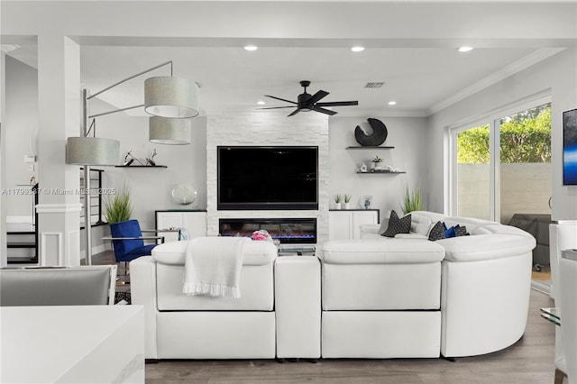 living room featuring a ceiling fan, ornamental molding, wood finished floors, recessed lighting, and a fireplace