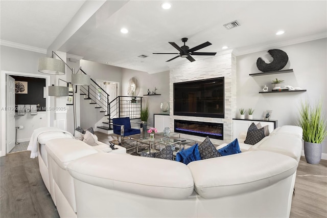 living area with a ceiling fan, crown molding, wood finished floors, stairway, and recessed lighting