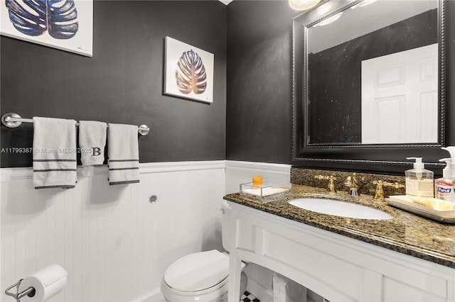 bathroom featuring toilet, wainscoting, and vanity