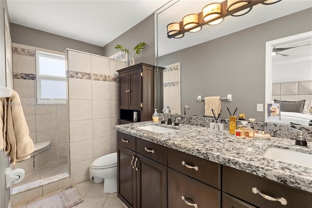 bathroom featuring tile patterned floors, toilet, double vanity, and a walk in shower