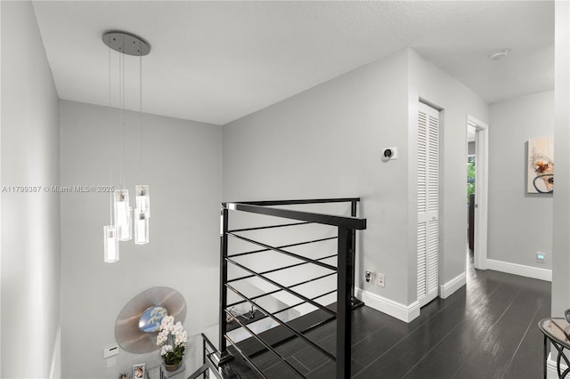 hall with dark wood-style flooring and baseboards