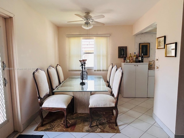 dining area featuring light tile patterned floors, a ceiling fan, and baseboards