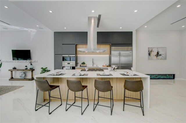 1780 Chucunantah Rd, Miami, FL 33133 - kitchen featuring appliances with stainless steel finishes, modern cabinets, island exhaust hood, light marble finish floors, and recessed lighting