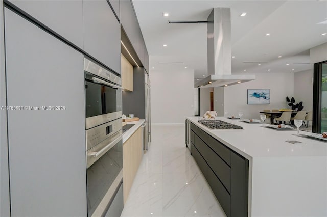 1780 Chucunantah Rd, Miami, FL 33133 - kitchen with modern cabinets, light marble finish floors, island exhaust hood, stainless steel gas stovetop, and light countertops