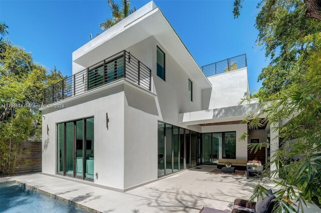 1780 Chucunantah Rd, Miami, FL 33133 - back of house with an outdoor hangout area, a patio, stucco siding, a balcony, and an outdoor pool