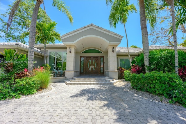 doorway to property featuring a tiled roof and stucco siding