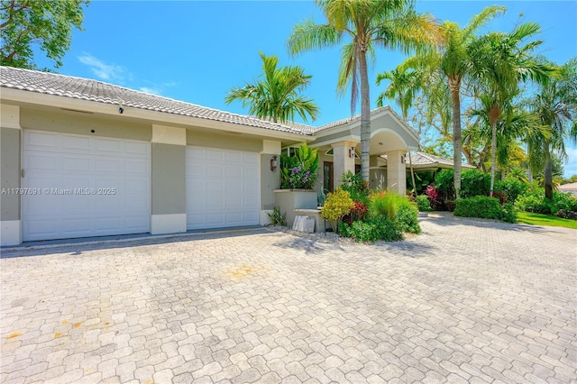 view of front of property with decorative driveway, a tiled roof, stucco siding, and a garage