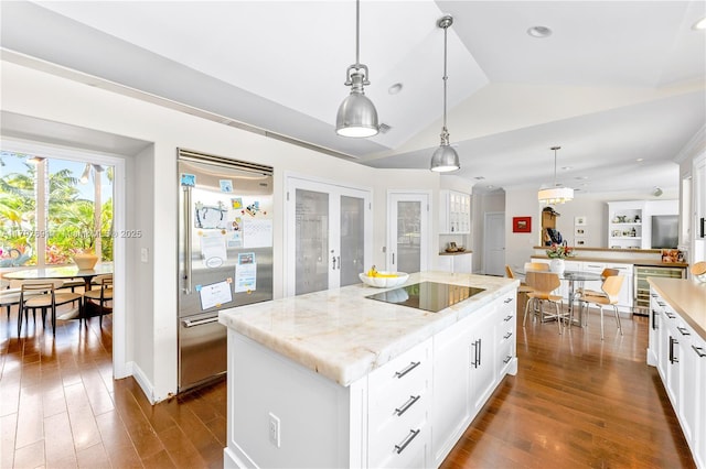 kitchen featuring appliances with stainless steel finishes, lofted ceiling, dark wood-type flooring, hanging light fixtures, and white cabinetry