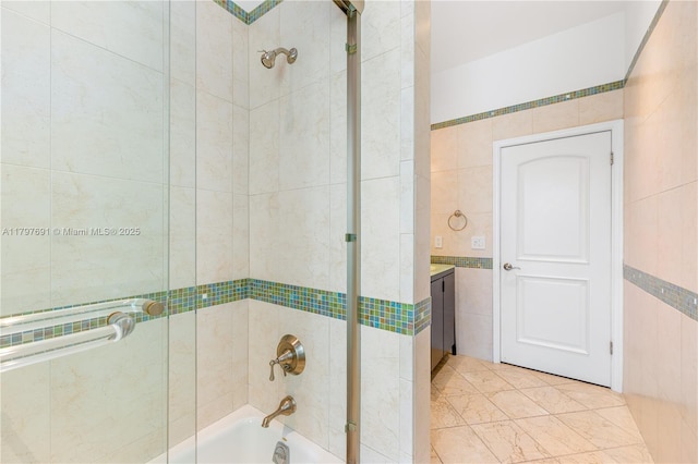 full bathroom featuring tile walls, enclosed tub / shower combo, and vanity