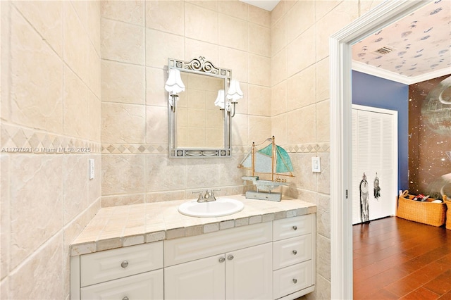 bathroom featuring tile walls, vanity, crown molding, and wood finished floors