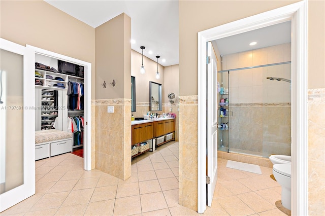 bathroom with tile walls, tile patterned flooring, a shower stall, vanity, and wainscoting