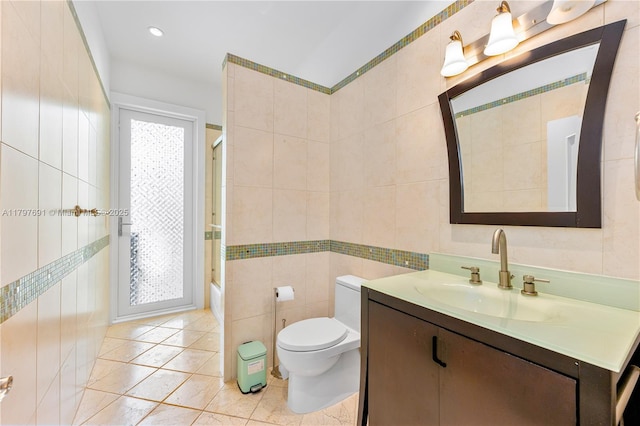 bathroom with tile walls, vanity, toilet, tile patterned flooring, and shower / bath combination with glass door
