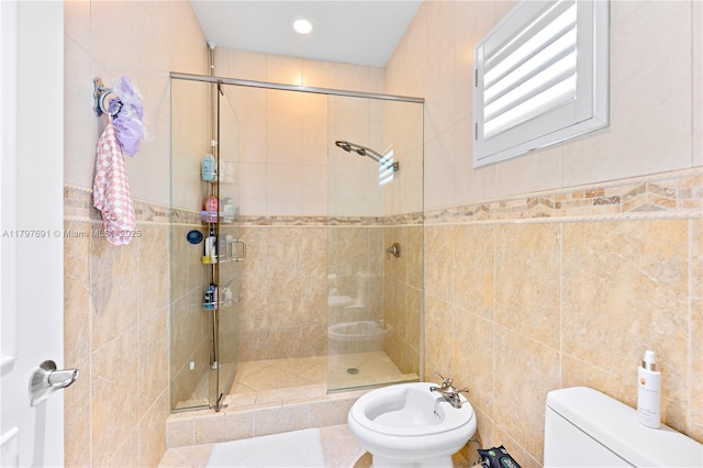 bathroom featuring tile walls, a stall shower, toilet, and a bidet
