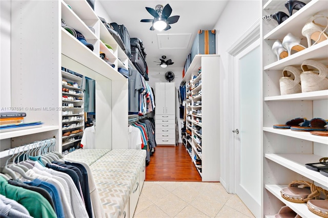 walk in closet with attic access, tile patterned flooring, and a ceiling fan