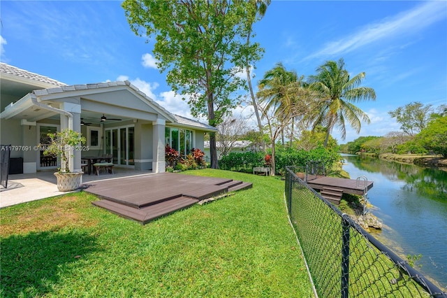 view of yard featuring ceiling fan and a deck with water view