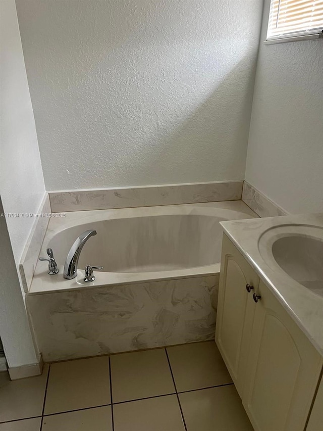 bathroom featuring tile patterned floors, a bath, vanity, and a textured wall