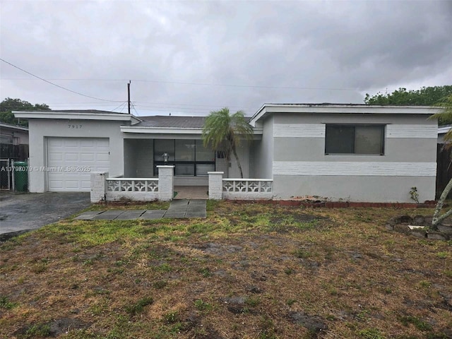 7917 Juniper St, Miramar, FL 33023 - ranch-style house with covered porch, an attached garage, asphalt driveway, and stucco siding