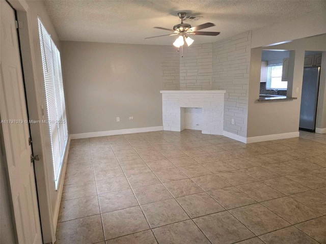 7917 Juniper St, Miramar, FL 33023 - unfurnished living room featuring a textured ceiling, a ceiling fan, light tile patterned flooring, a sink, and a fireplace