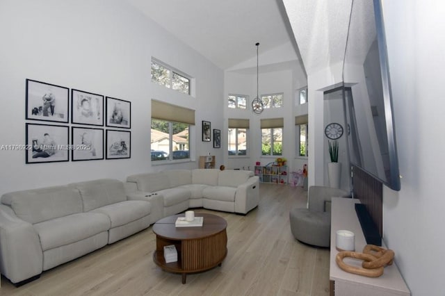 living area featuring light wood-style floors, a chandelier, and high vaulted ceiling