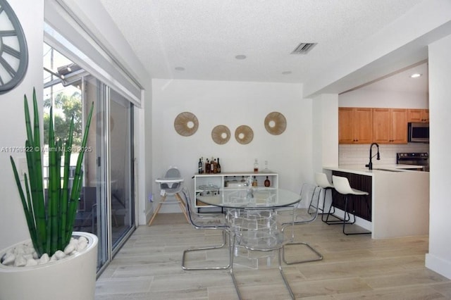 dining room featuring a textured ceiling, light wood-style flooring, and recessed lighting