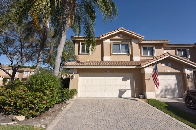 multi unit property with a tile roof, stucco siding, decorative driveway, and an attached garage