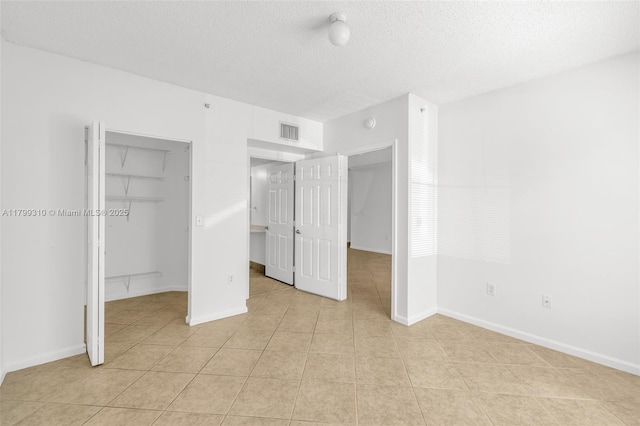 11643 W Atlantic Blvd Unit 1101, Coral Springs, FL 33071 - unfurnished bedroom featuring light tile patterned floors, a closet, a textured ceiling, a spacious closet, and baseboards