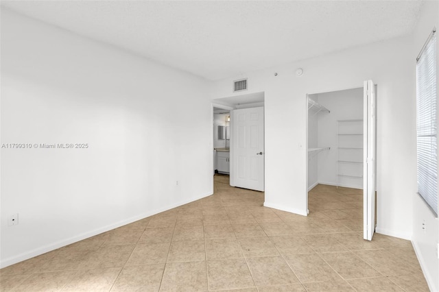 11643 W Atlantic Blvd Unit 1101, Coral Springs, FL 33071 - unfurnished bedroom featuring light tile patterned floors, a walk in closet, baseboards, and a closet