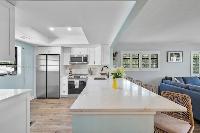 1779 NE 39th Ct Unit 1107, Pompano Beach, FL 33064 - kitchen with stainless steel appliances, a sink, light wood finished floors, a peninsula, and open floor plan