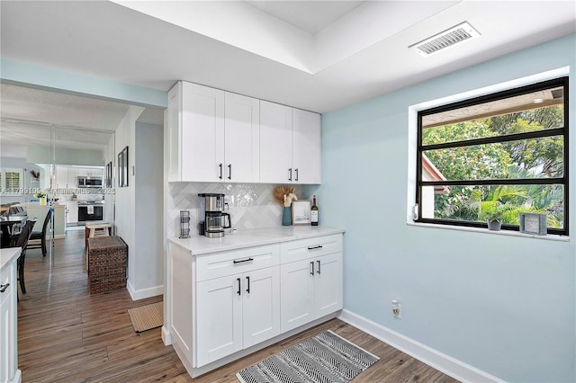 1779 NE 39th Ct Unit 1107, Pompano Beach, FL 33064 - kitchen featuring decorative backsplash, stainless steel appliances, wood finished floors, and white cabinets