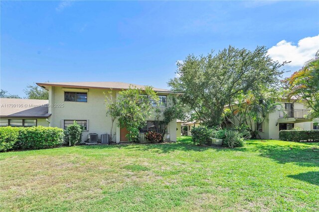 1779 NE 39th Ct Unit 1107, Pompano Beach, FL 33064 - rear view of property featuring stucco siding, a lawn, and central AC