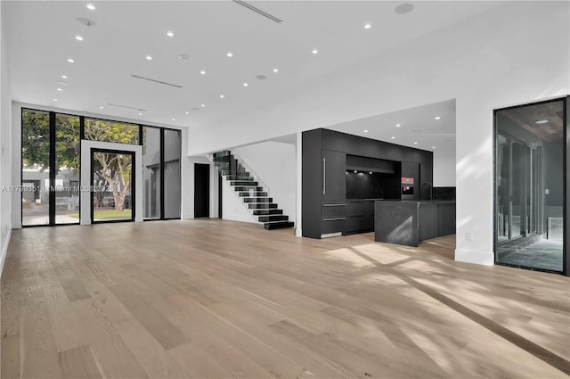 30 NE 50th St, Miami, FL 33137 - unfurnished living room featuring expansive windows, recessed lighting, stairway, a sink, and light wood finished floors