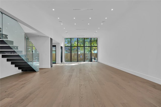 30 NE 50th St, Miami, FL 33137 - unfurnished living room featuring a wall of windows, light wood-style flooring, stairway, recessed lighting, and baseboards