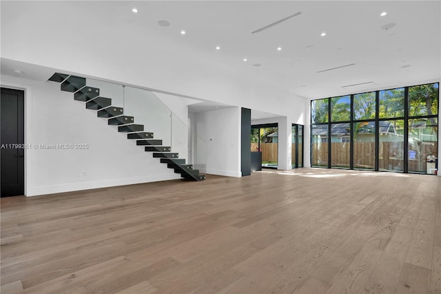 30 NE 50th St, Miami, FL 33137 - unfurnished living room with stairs, light wood-style floors, baseboards, a wall of windows, and recessed lighting