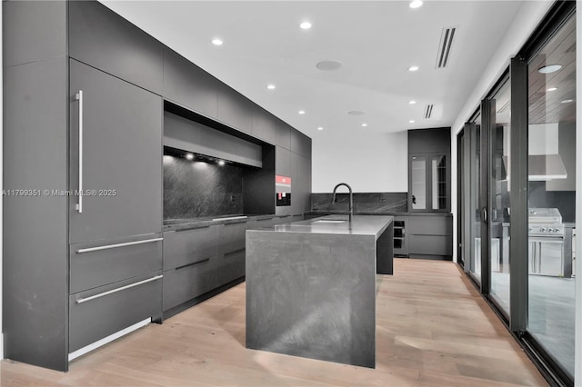 30 NE 50th St, Miami, FL 33137 - kitchen with modern cabinets, recessed lighting, light wood-type flooring, an island with sink, and tasteful backsplash