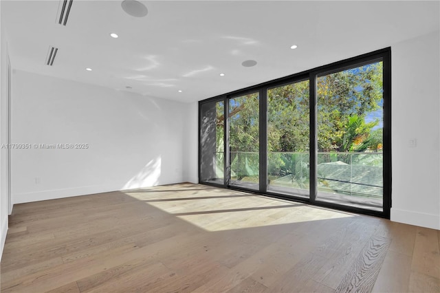 30 NE 50th St, Miami, FL 33137 - spare room featuring floor to ceiling windows, healthy amount of natural light, wood finished floors, recessed lighting, and baseboards
